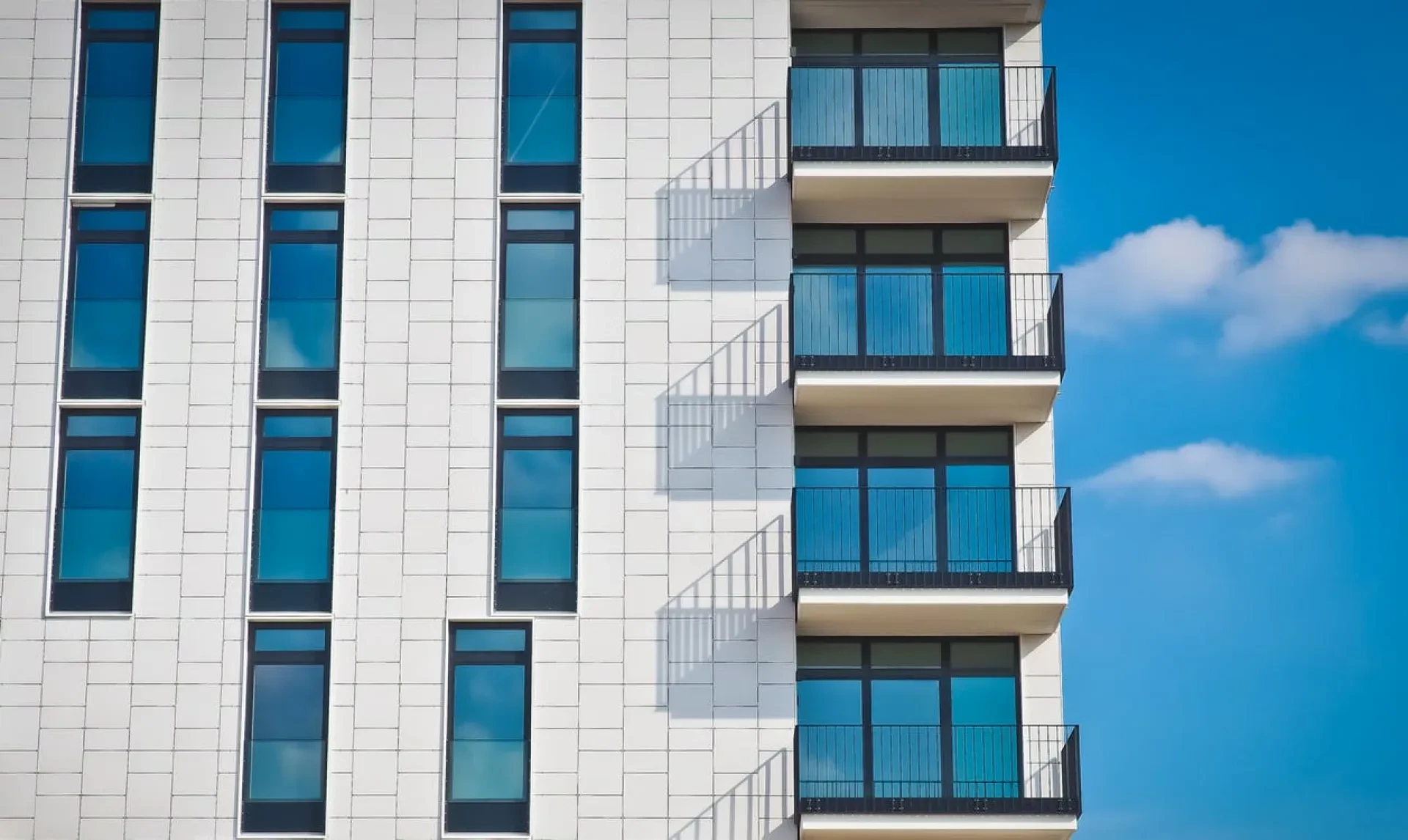 Modernes Wohngebäude mit Balkonen und großen Fenstern vor blauem Himmel