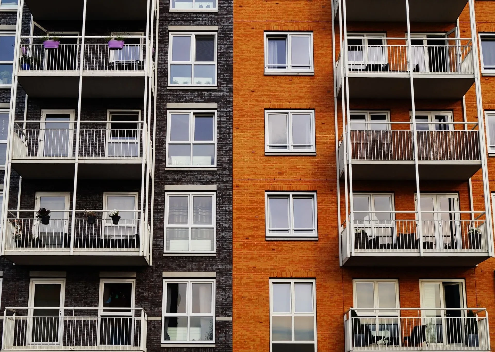 Fassade zweier Mehrfamilienhäuser mit Balkonen in dunkelgrau und orange