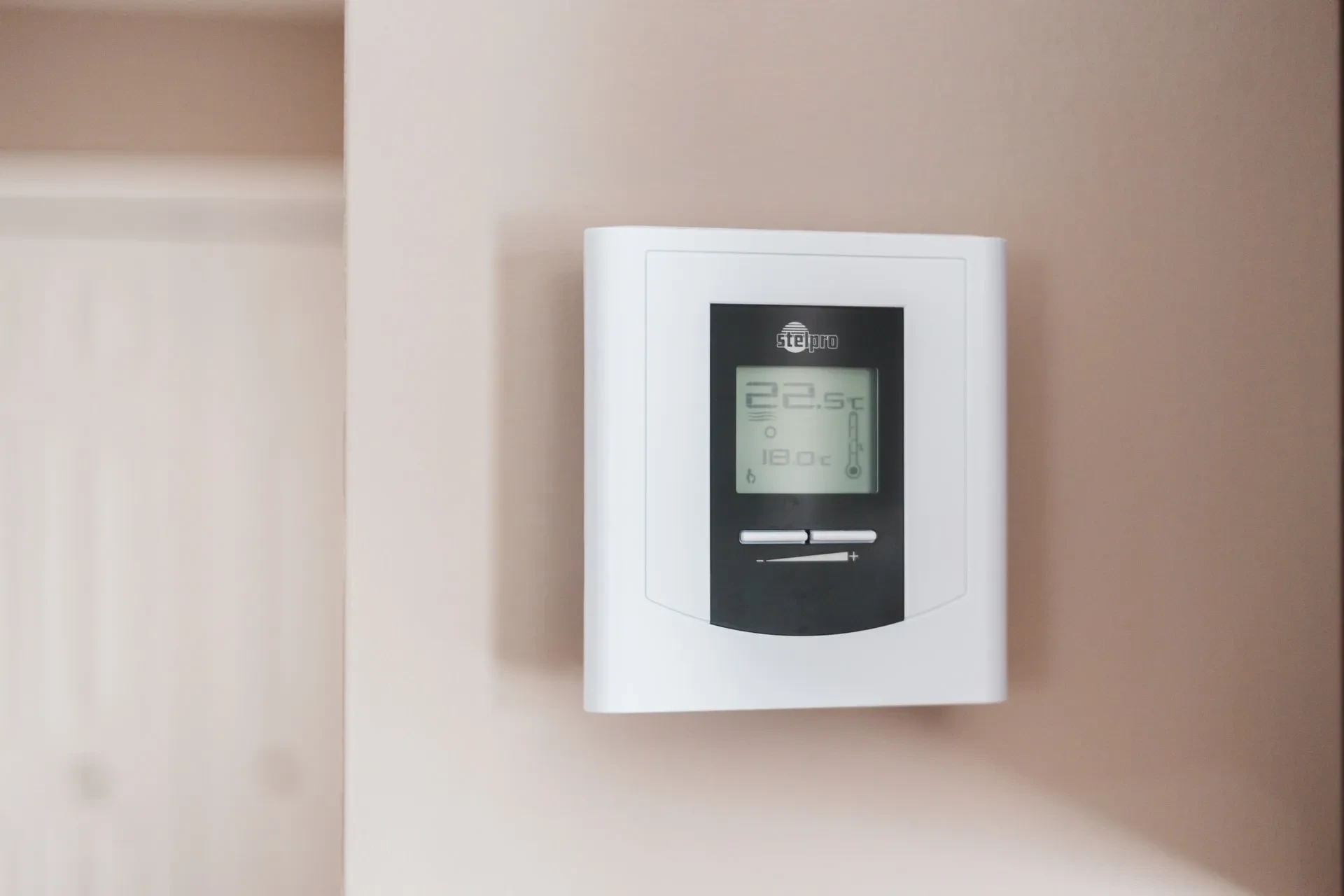 Digitaler Thermostat an der Wand mit Temperaturanzeige