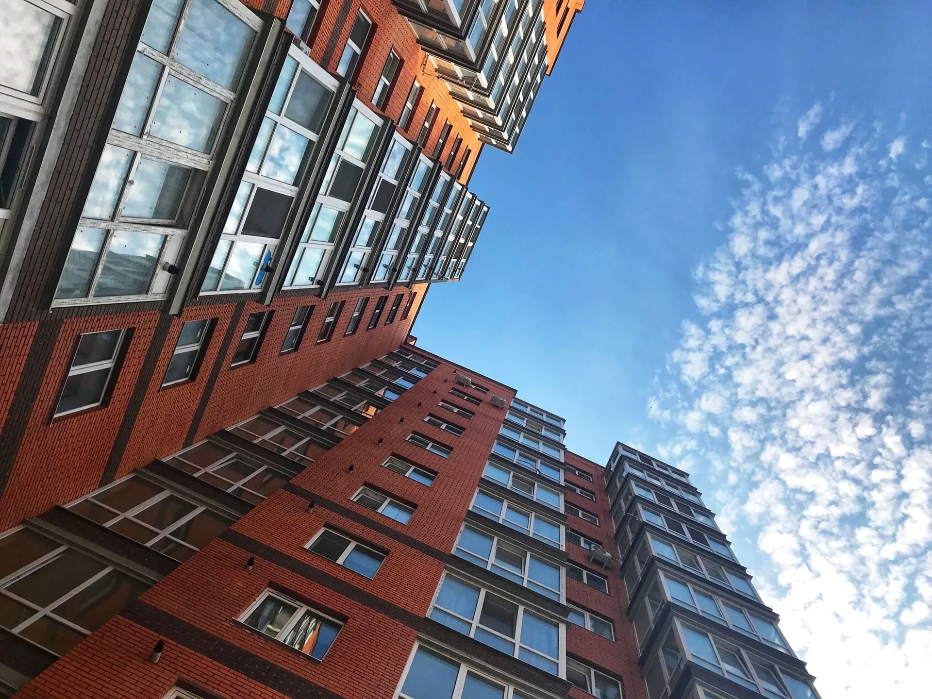 Froschperspektive auf mehrstöckige Backsteingebäude vor blauem Himmel