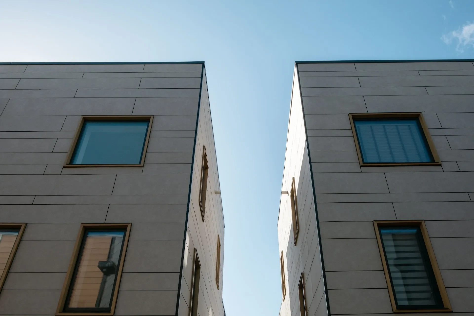 Zwei moderne Wohngebäude mit heller Fassade von unten fotografiert vor blauem Himmel