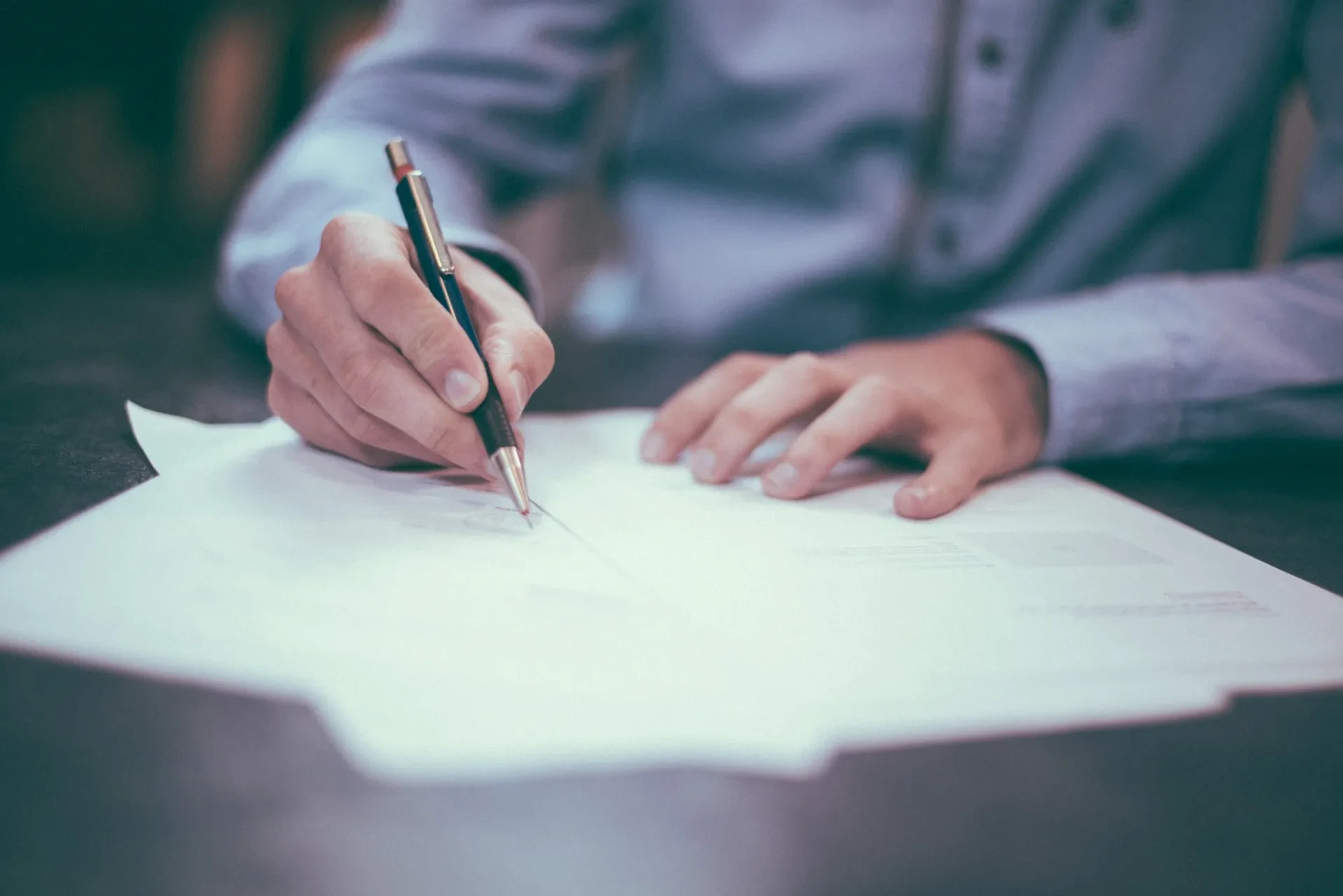 Person unterschreibt Dokument mit Stift