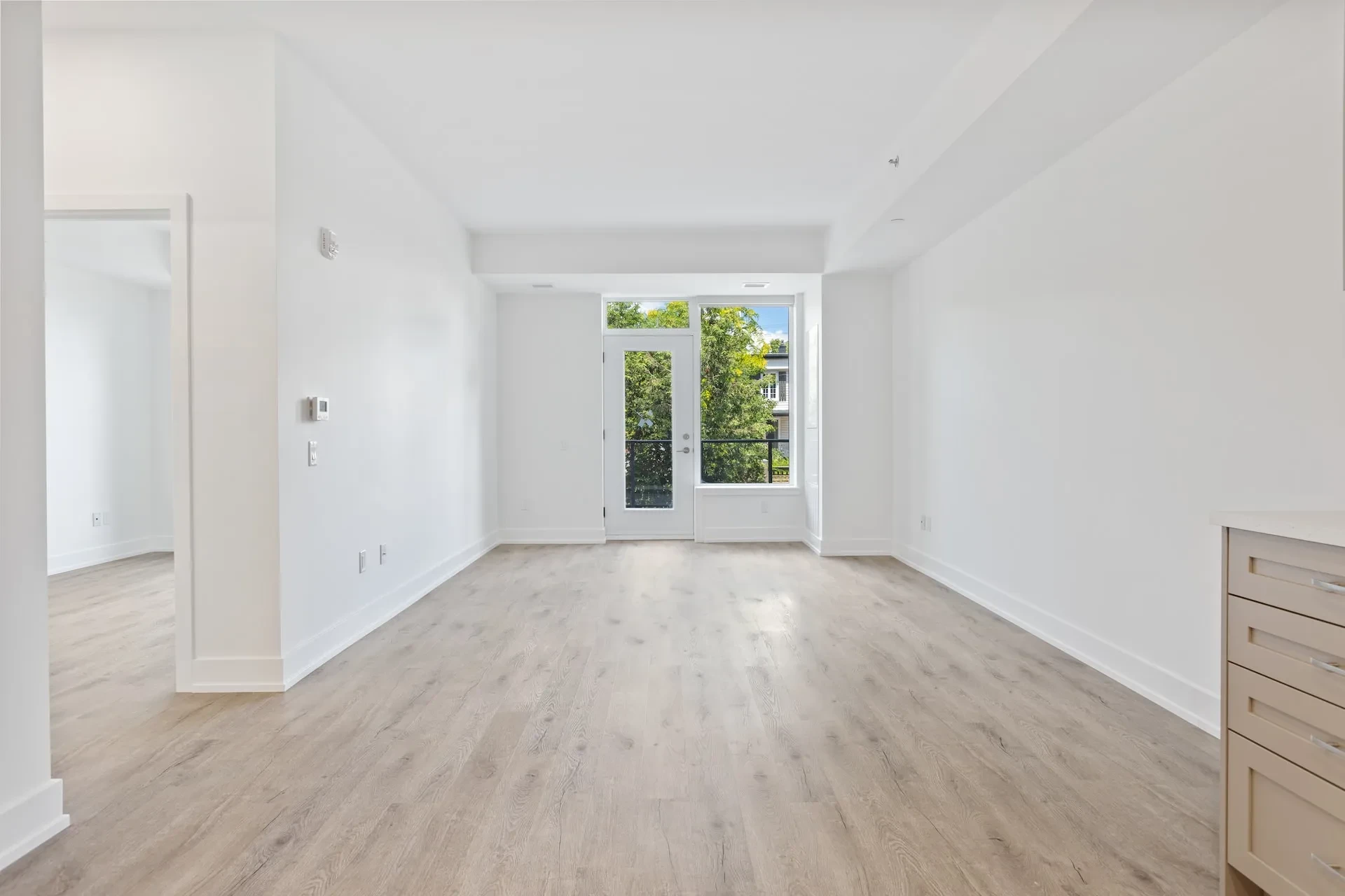 Leeres helles Wohnzimmer mit Holzboden und Balkontür