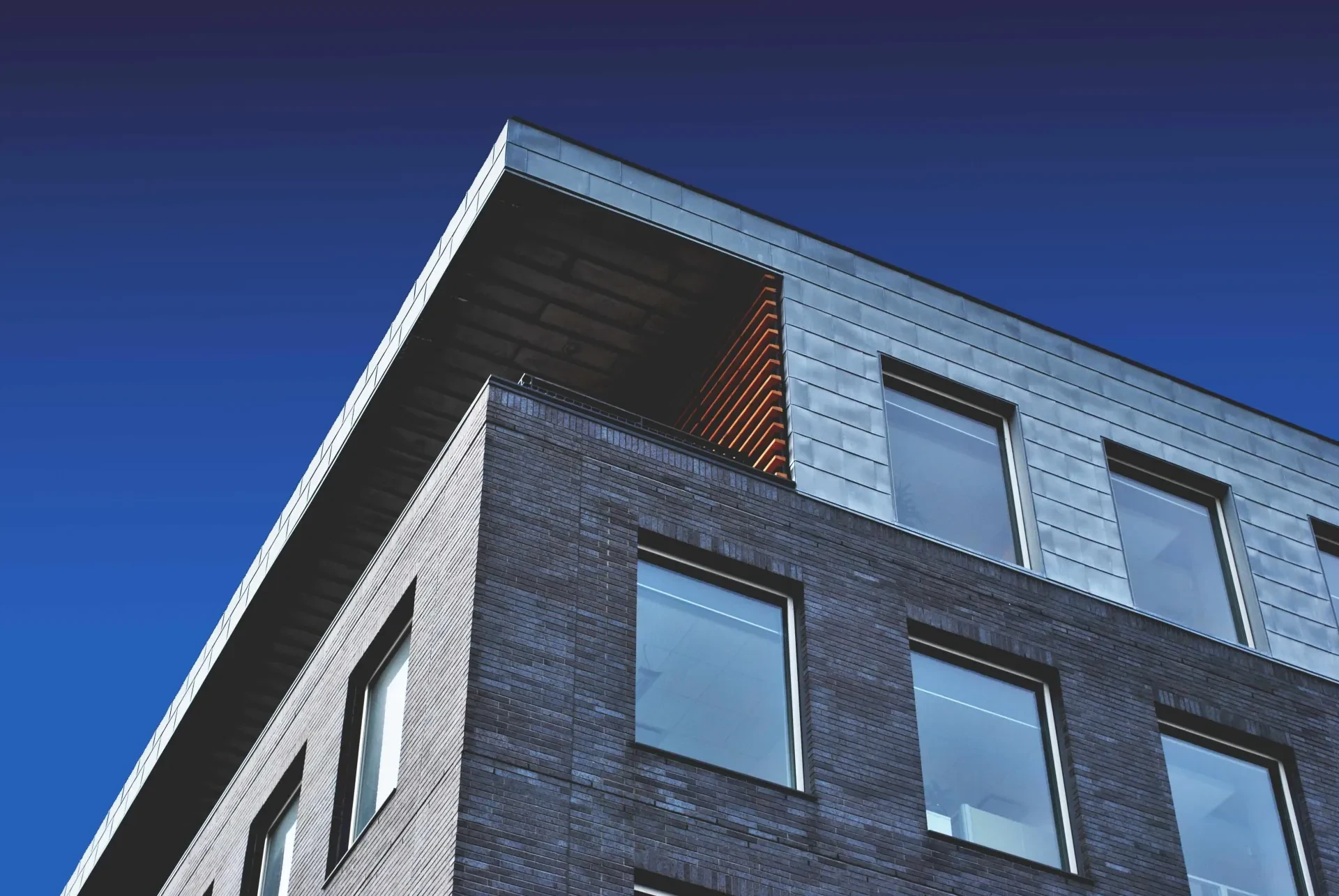 Modernes Mehrfamilienhaus aus Backstein vor blauem Himmel